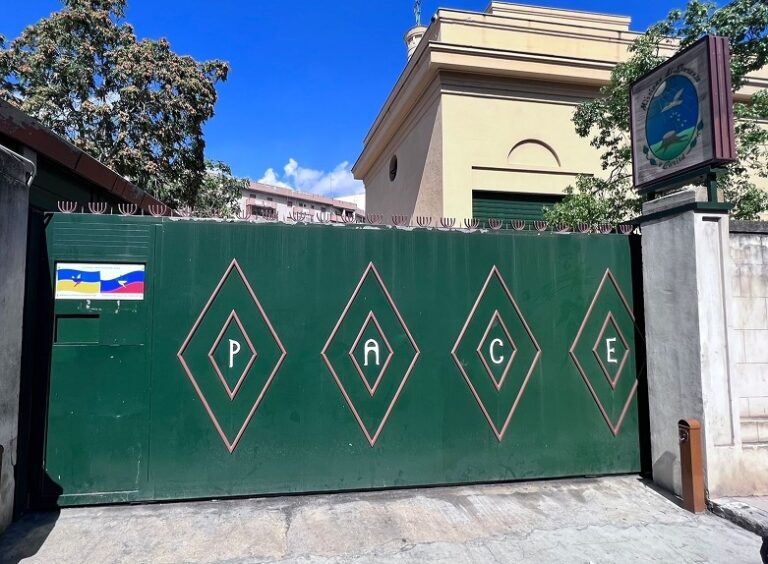 Cartelli con bandiere dell’Ucraina e della Russia agli ingressi delle missioni “Speranza e Carità”